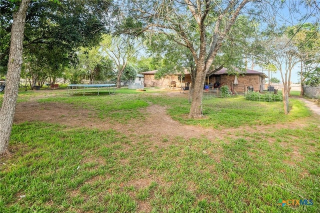 view of yard featuring a trampoline and fence