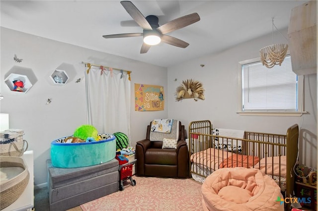 bedroom with a nursery area and a ceiling fan