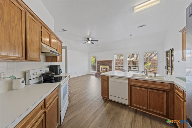 kitchen featuring hanging light fixtures, vaulted ceiling, sink, and white appliances