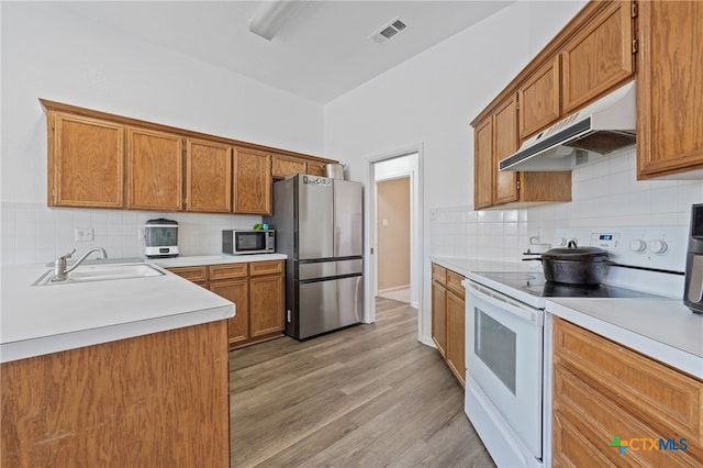 kitchen with tasteful backsplash, appliances with stainless steel finishes, sink, and light wood-type flooring