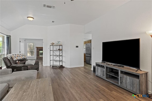 living room featuring lofted ceiling, a brick fireplace, and dark hardwood / wood-style floors