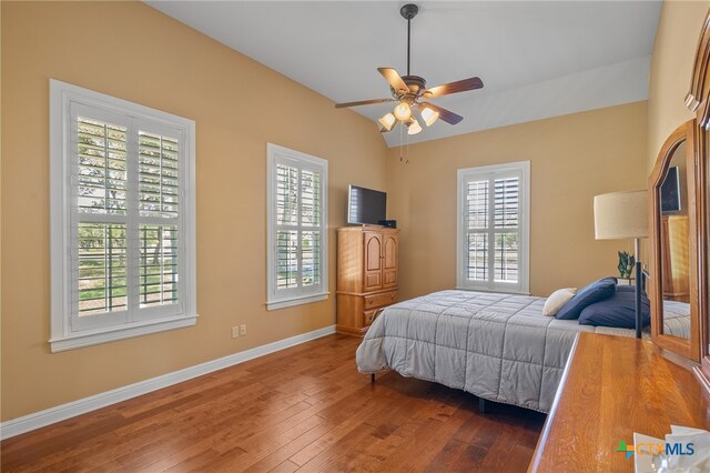 bedroom featuring vaulted ceiling, dark wood-type flooring, a ceiling fan, and baseboards