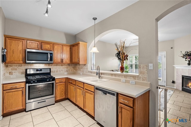 kitchen with tasteful backsplash, appliances with stainless steel finishes, a sink, and a tile fireplace