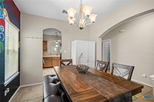 dining space featuring arched walkways, light tile patterned flooring, healthy amount of natural light, and a chandelier