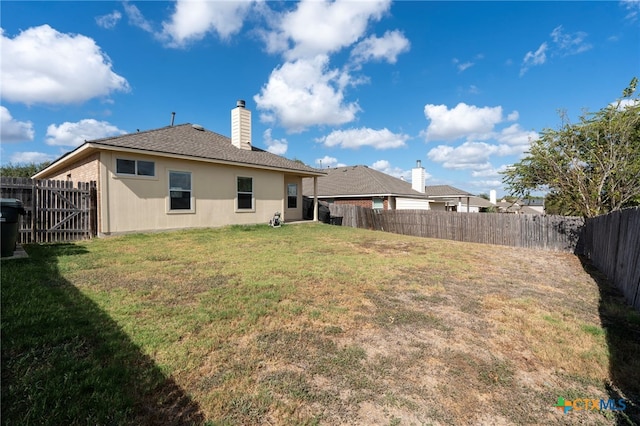 back of property featuring a yard, a chimney, and a fenced backyard