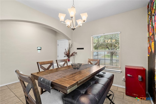 dining room featuring an inviting chandelier, baseboards, light tile patterned floors, and arched walkways