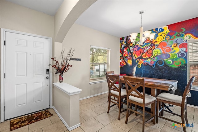 dining space featuring arched walkways, light tile patterned floors, and baseboards