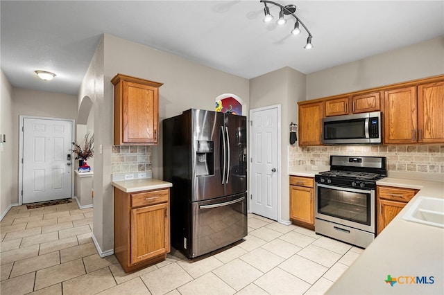 kitchen featuring light countertops, appliances with stainless steel finishes, and brown cabinetry