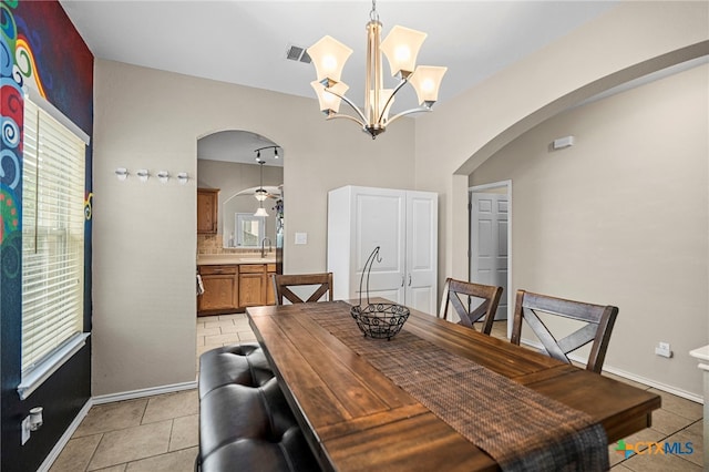 dining area featuring baseboards, visible vents, arched walkways, light tile patterned flooring, and ceiling fan with notable chandelier