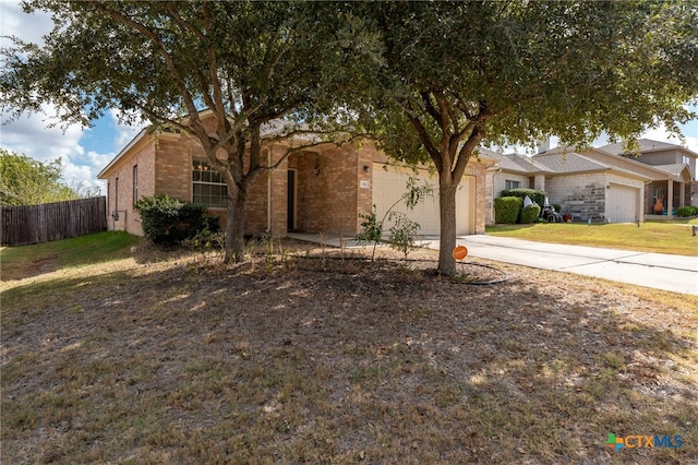 ranch-style home featuring brick siding, concrete driveway, an attached garage, a front yard, and fence