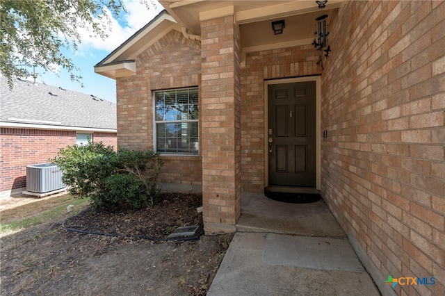 doorway to property featuring brick siding and cooling unit