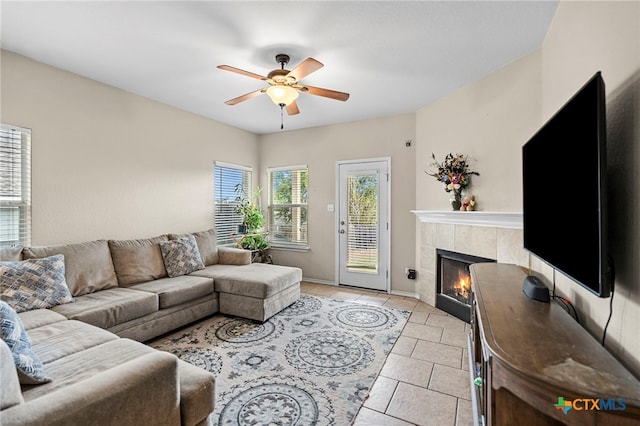 living room with light tile patterned flooring, a fireplace, a ceiling fan, and baseboards