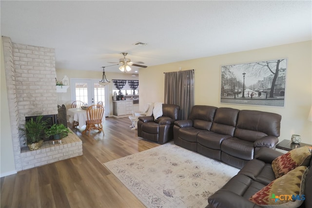 living room with a fireplace, light wood-type flooring, and ceiling fan