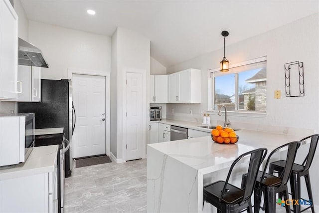 kitchen featuring white cabinetry, decorative light fixtures, kitchen peninsula, stainless steel appliances, and light stone countertops