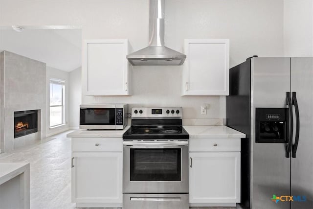 kitchen with stainless steel appliances, white cabinetry, and wall chimney range hood