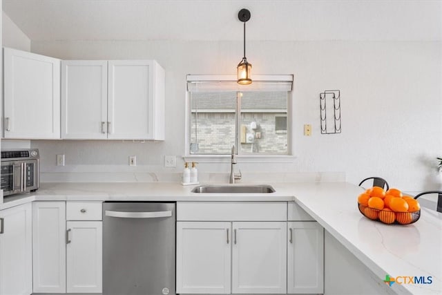 kitchen featuring pendant lighting, sink, dishwasher, white cabinetry, and light stone counters