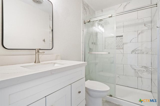 bathroom with vanity, toilet, and a shower with door