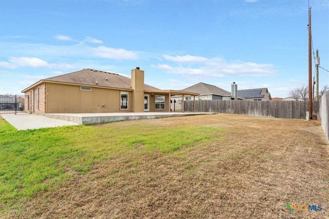 back of house with a lawn and a patio