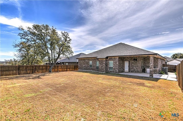 rear view of property featuring brick siding, cooling unit, a yard, a fenced backyard, and a patio area