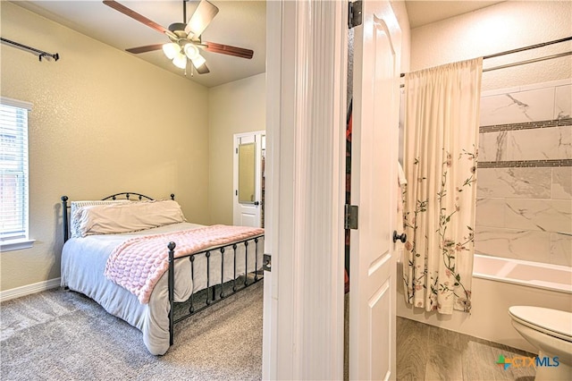 carpeted bedroom featuring ceiling fan, a textured wall, baseboards, and connected bathroom