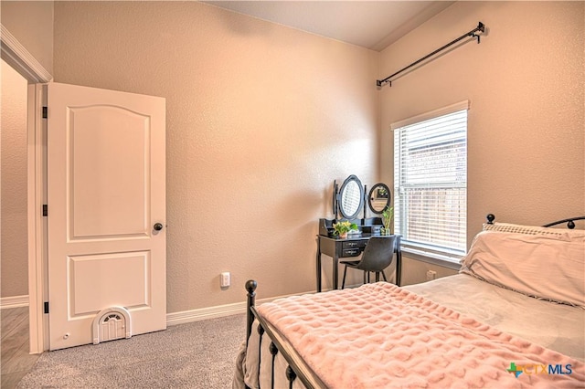 bedroom featuring light colored carpet, baseboards, and a textured wall