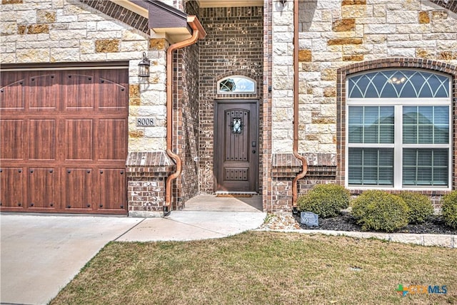 property entrance featuring a garage and stone siding