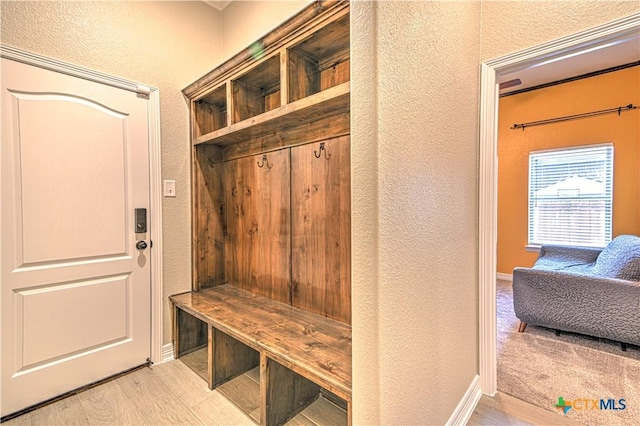 mudroom with baseboards, wood finished floors, and a textured wall