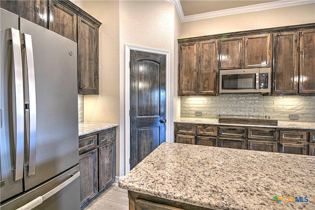 kitchen featuring crown molding, tasteful backsplash, dark brown cabinetry, and stainless steel appliances