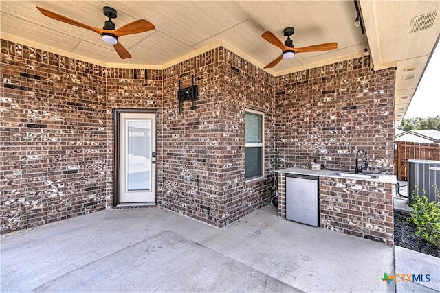 view of patio / terrace featuring visible vents, ceiling fan, fence, central AC unit, and a sink