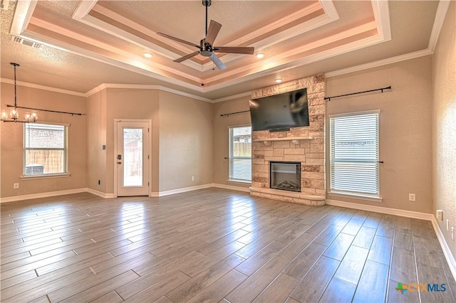 unfurnished living room featuring a tray ceiling, visible vents, wood finished floors, and ornamental molding