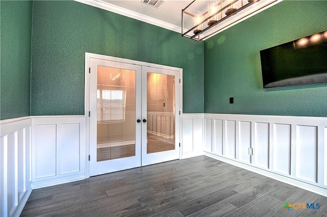 spare room featuring dark wood-type flooring, crown molding, french doors, and a wainscoted wall