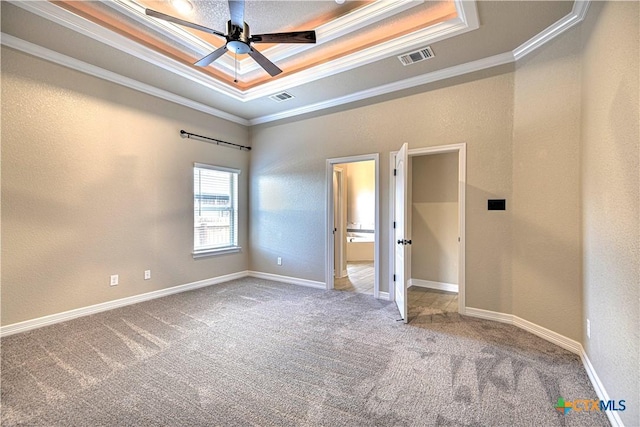 unfurnished bedroom featuring a tray ceiling, crown molding, visible vents, and carpet floors