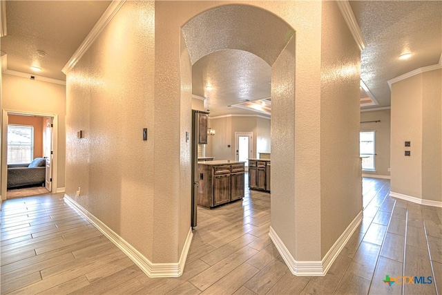 hallway featuring arched walkways, plenty of natural light, wood tiled floor, and a textured wall