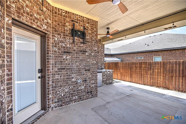 view of patio / terrace featuring a sink, fence, and ceiling fan