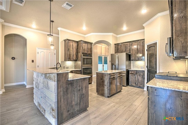 kitchen featuring arched walkways, visible vents, appliances with stainless steel finishes, and dark brown cabinetry