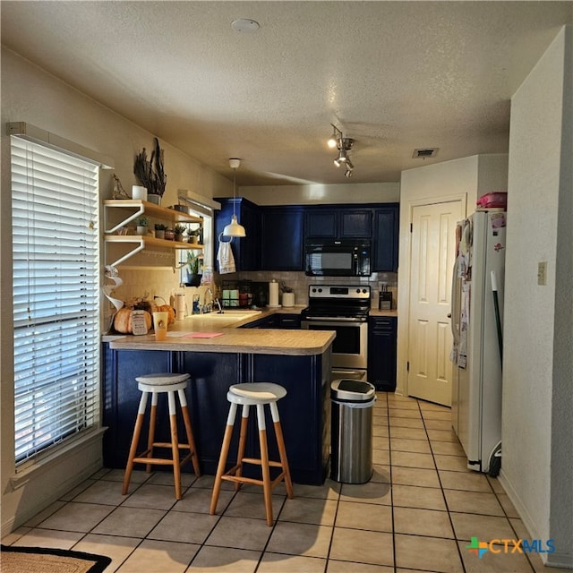 kitchen featuring electric range, tasteful backsplash, white fridge, a kitchen bar, and kitchen peninsula