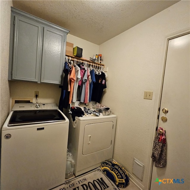 washroom featuring cabinets, a textured ceiling, and washing machine and clothes dryer