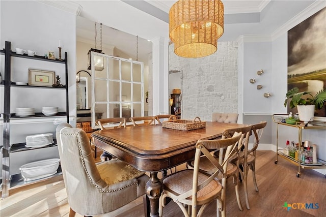 dining room with an inviting chandelier, crown molding, light hardwood / wood-style flooring, and a raised ceiling