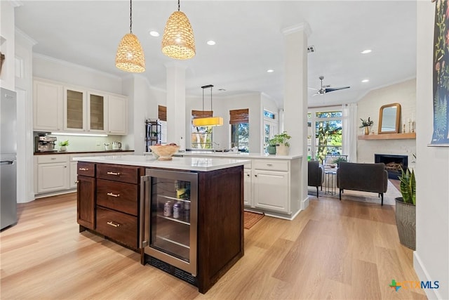 kitchen with white cabinetry, beverage cooler, decorative light fixtures, and dark brown cabinets