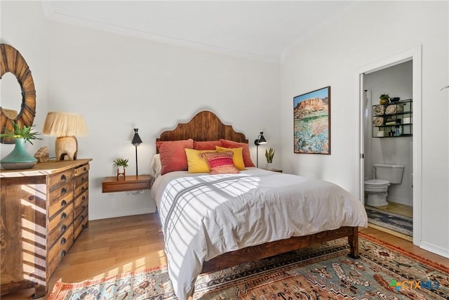 bedroom featuring crown molding, ensuite bathroom, and light hardwood / wood-style flooring