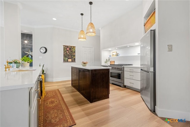 kitchen with sink, a center island, dark brown cabinets, appliances with stainless steel finishes, and light hardwood / wood-style floors