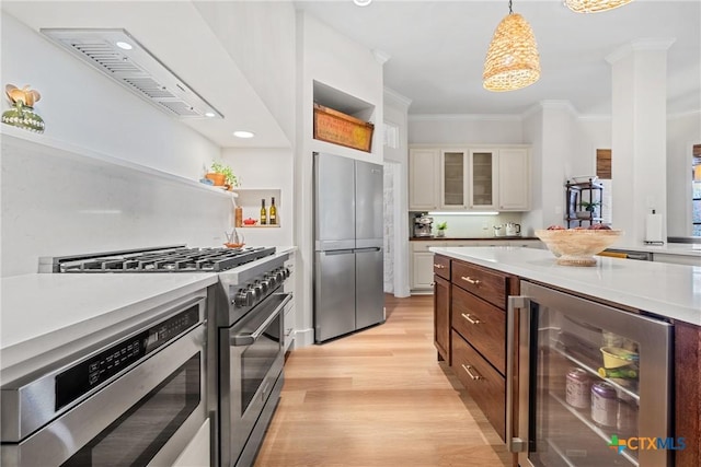 kitchen featuring light hardwood / wood-style flooring, hanging light fixtures, appliances with stainless steel finishes, beverage cooler, and white cabinets