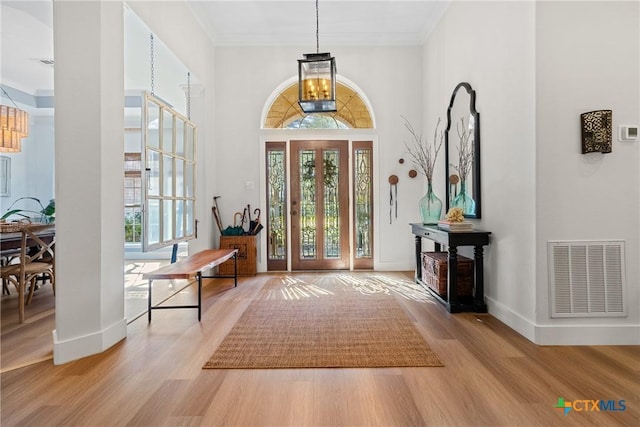 foyer entrance featuring ornamental molding, hardwood / wood-style floors, and a notable chandelier