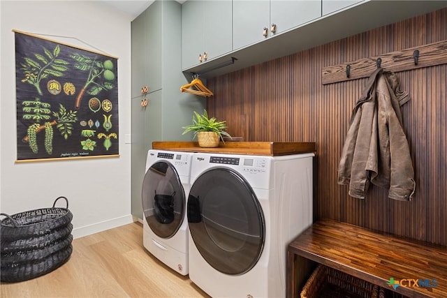 washroom with cabinets, washing machine and dryer, and light hardwood / wood-style flooring