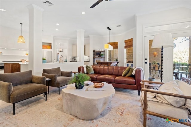 living room featuring ornate columns, crown molding, and ceiling fan