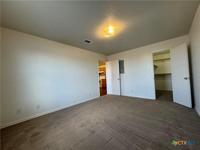unfurnished bedroom with a walk in closet, carpet, visible vents, and baseboards