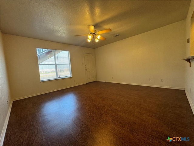 spare room with visible vents, baseboards, dark wood-style flooring, a ceiling fan, and a textured ceiling