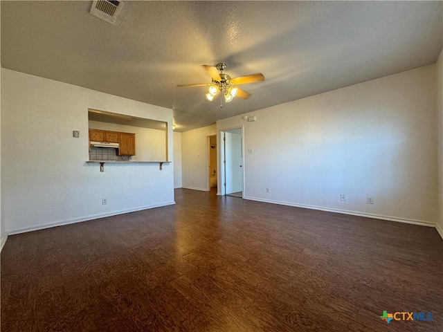 unfurnished living room featuring a ceiling fan, baseboards, dark wood-style floors, and visible vents