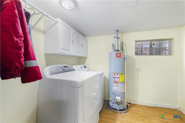 516 2nd St, Cuero, TX 77954 - laundry room featuring water heater, washer and dryer, light wood-style floors, and cabinet space
