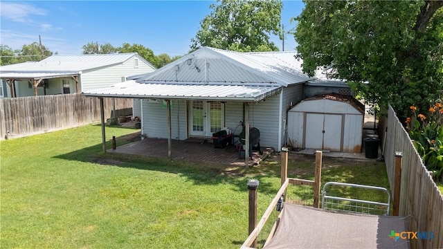 516 2nd St, Cuero, TX 77954 - back of property featuring a fenced backyard, a storage shed, a metal roof, and french doors